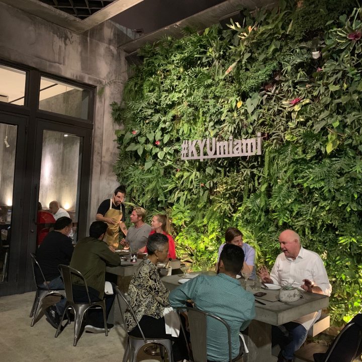 Restaurant guest at KYU in Miami, FL, dining in front of living green wall maintained by Miami Vertical Garden