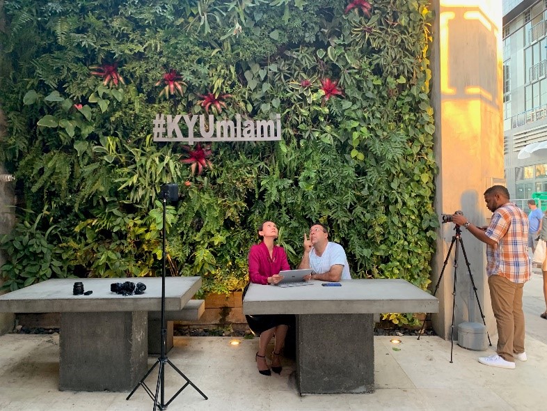 People sitting outside restaurant KYU in Miami, FL, dining in front of living green wall maintained by Miami Vertical Garden